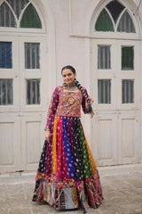 Woman in a colorful traditional outfit standing in front of a white building with arched windows.