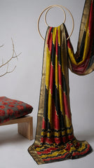 Colorful scarf with black, yellow, and red patterns draped over a chair against a white background