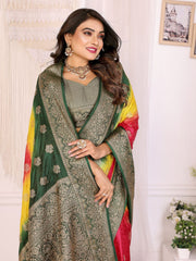 Woman wearing a traditional saree with a green and yellow pattern, standing against a white wall.