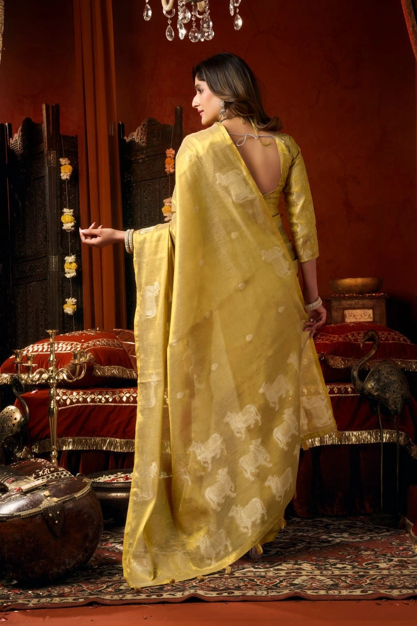 Woman in a yellow saree standing in a decorated room with red walls and furniture.