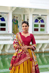 Woman in a red and yellow traditional outfit standing in front of a decorative building with colorful windows.
