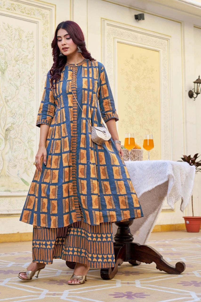 Woman in a blue and brown patterned outfit standing in an elegant room.