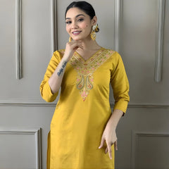 Woman wearing a yellow embroidered kurta against a gray wall
