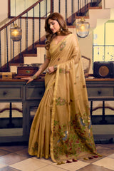 Woman wearing a beige saree with floral patterns in an indoor setting.