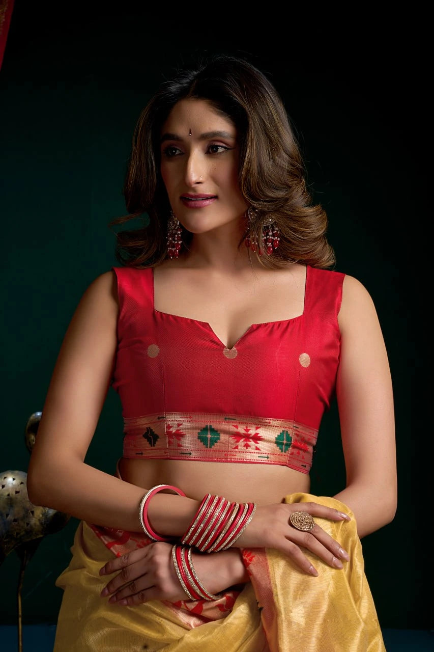 Woman wearing a red blouse with a yellow saree against a dark background