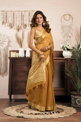 Woman in a yellow saree standing in a room with decorative elements.