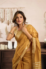 Woman in a yellow saree posing in a decorative setting with candles and decor items.