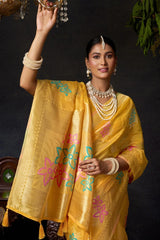Woman wearing a yellow saree with floral patterns against a dark background