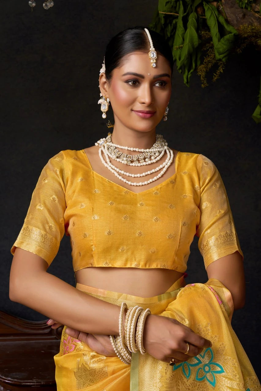 Woman in a yellow traditional outfit with jewelry against a dark background