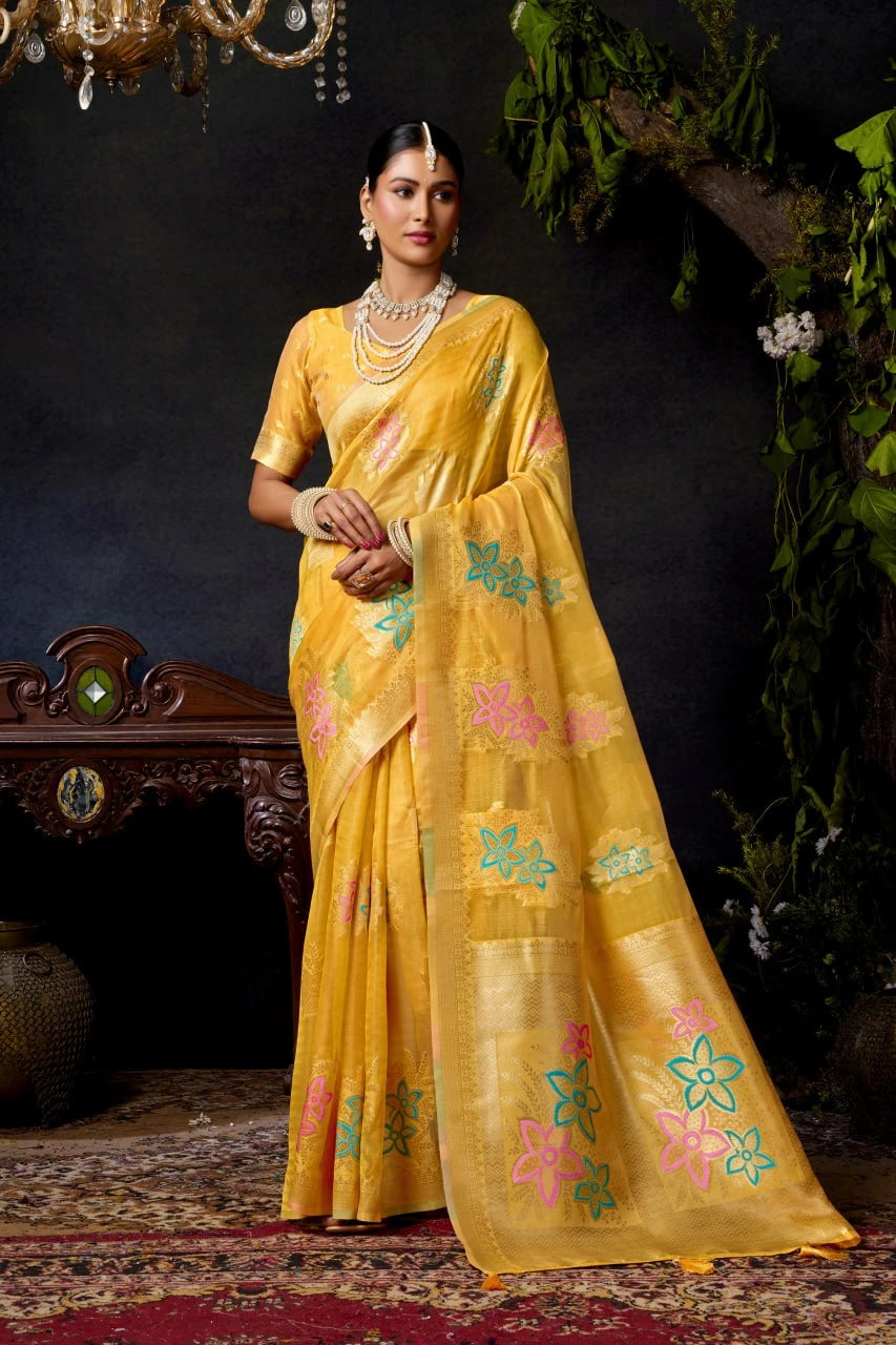 Woman in a yellow saree with floral patterns against a dark background