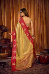 Woman in a yellow and red saree standing in a room with decorative items.