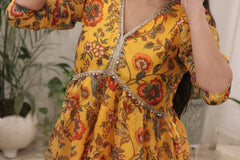 Yellow floral dress with intricate detailing on a blurred indoor background
