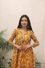 Woman wearing a yellow floral dress with a plain background