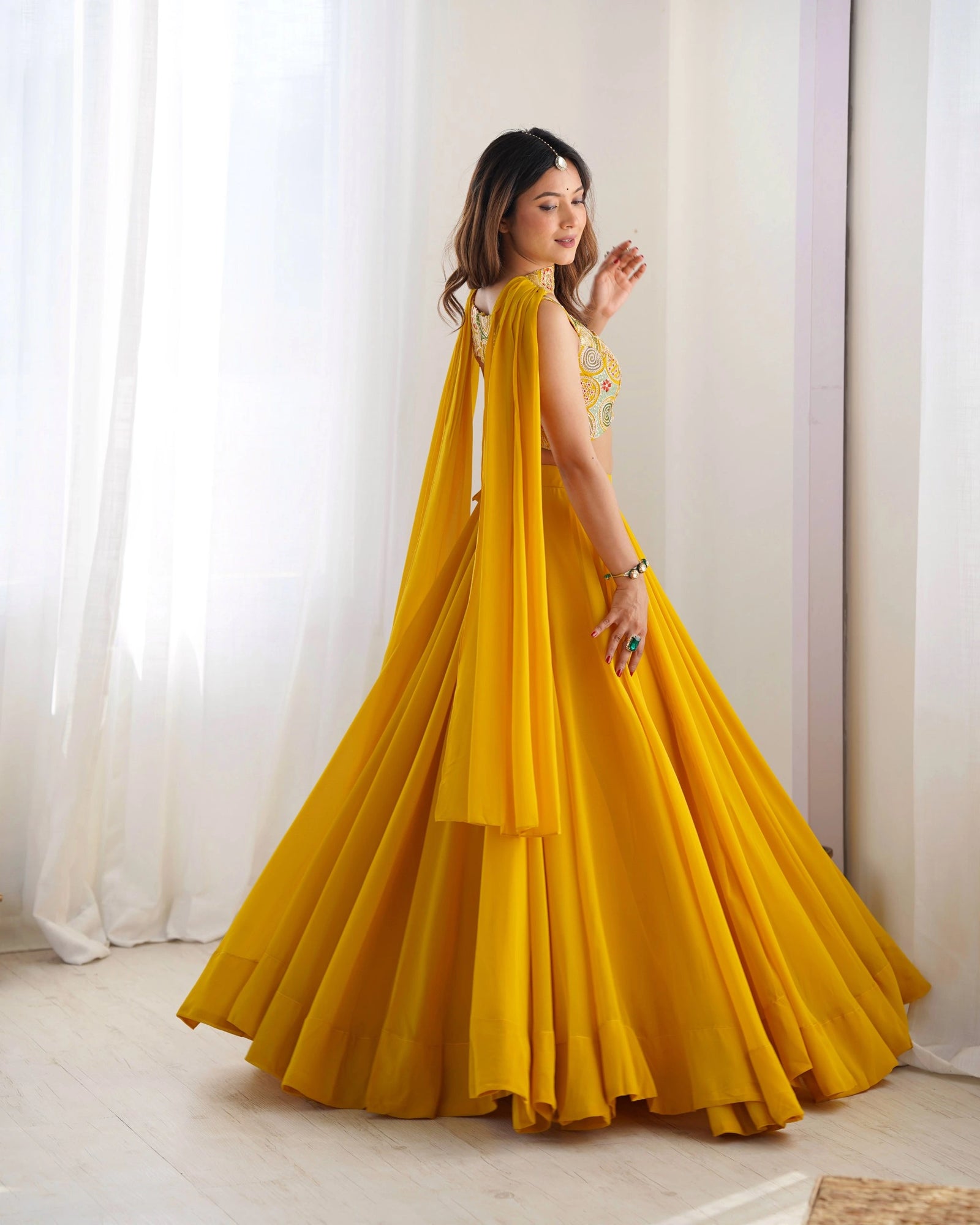 Woman in a yellow dress with a cape standing in a well-lit room.