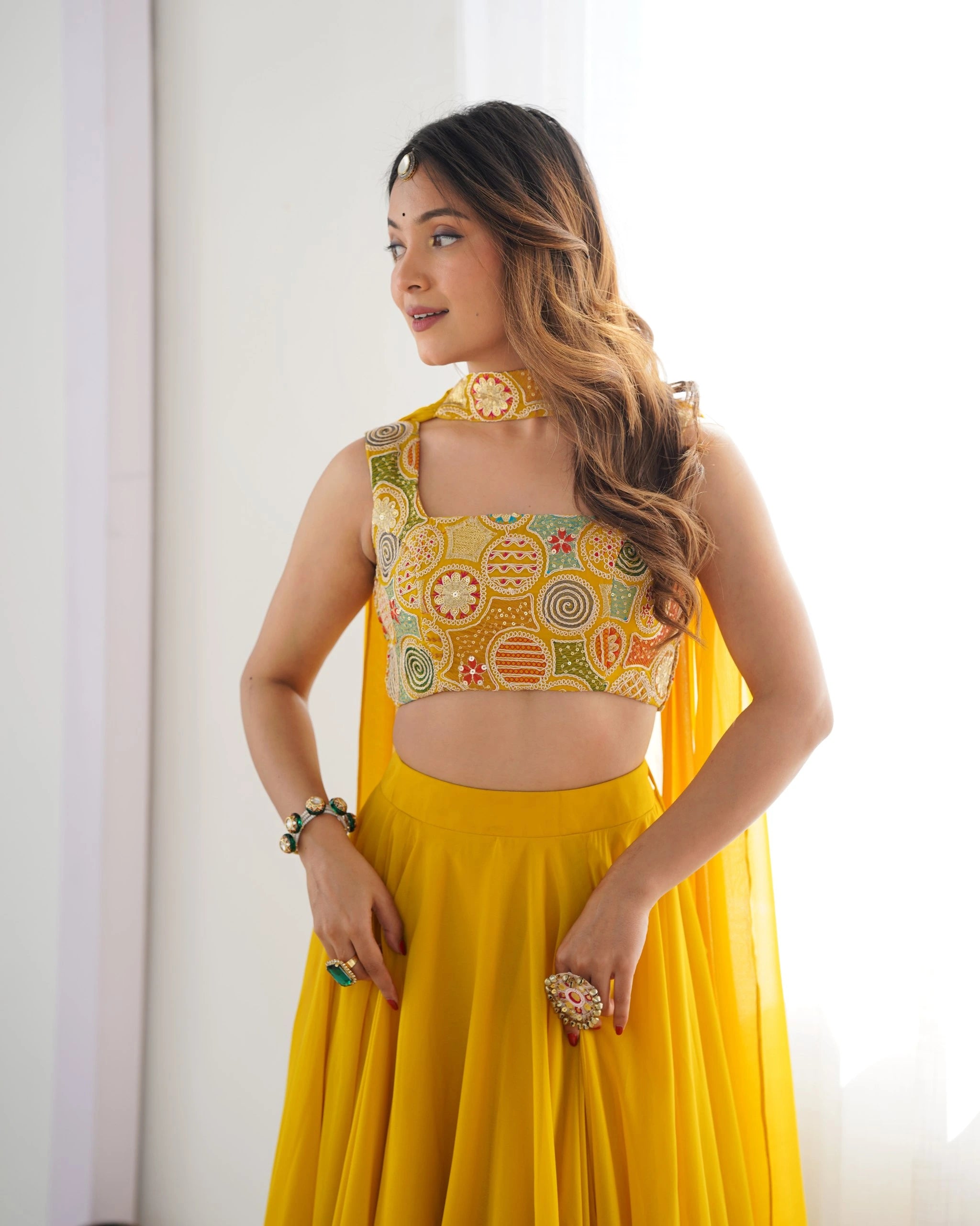Woman wearing a yellow traditional outfit with intricate designs.