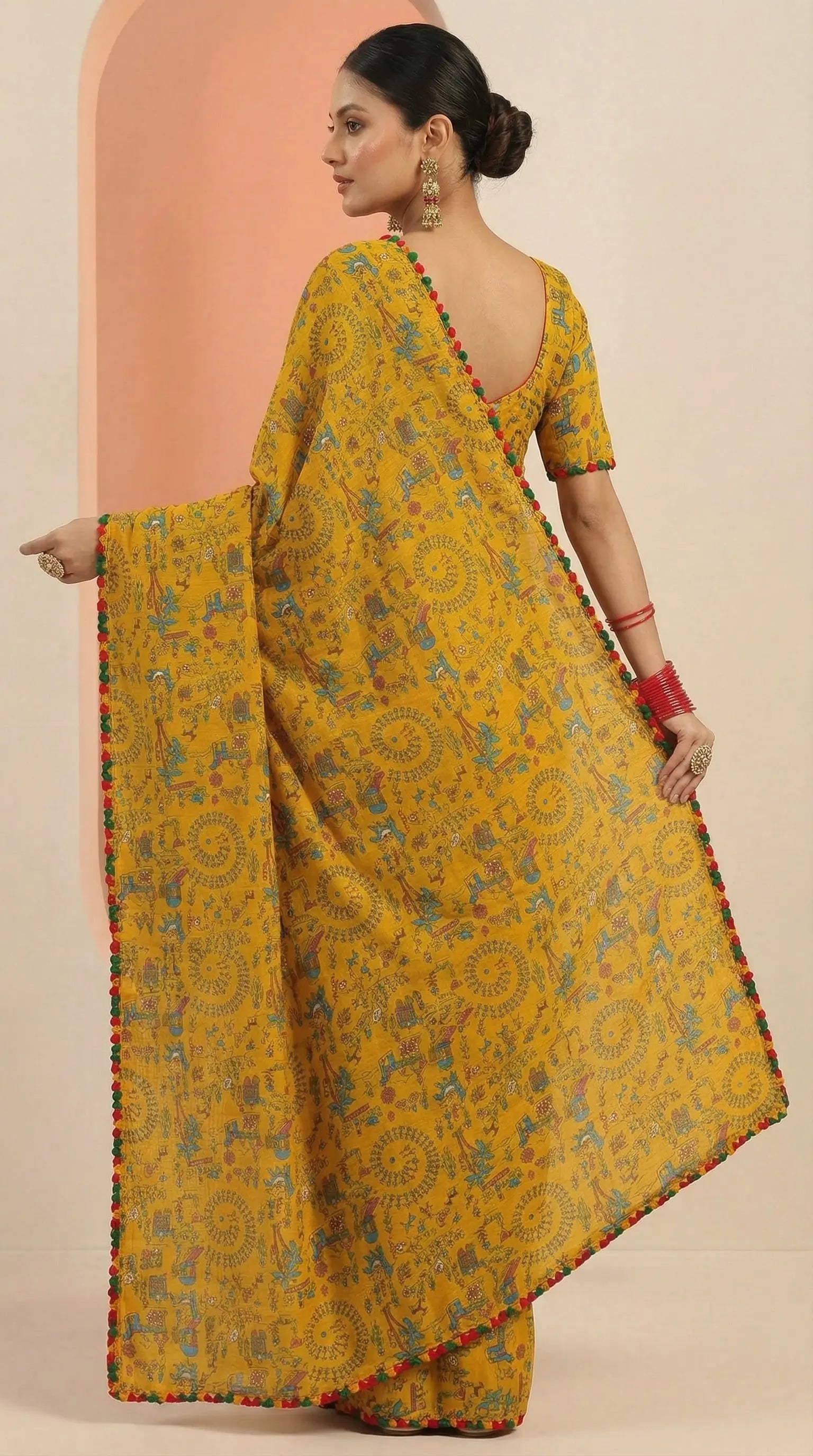 Woman wearing a yellow saree with a patterned border against a peach and beige background