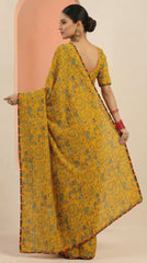 Woman wearing a yellow saree with a patterned border against a peach and beige background