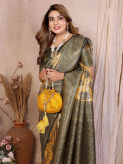 Woman in a traditional saree holding a yellow bag against a neutral background