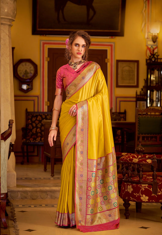 Woman in a yellow saree with a pink blouse in an ornate room.