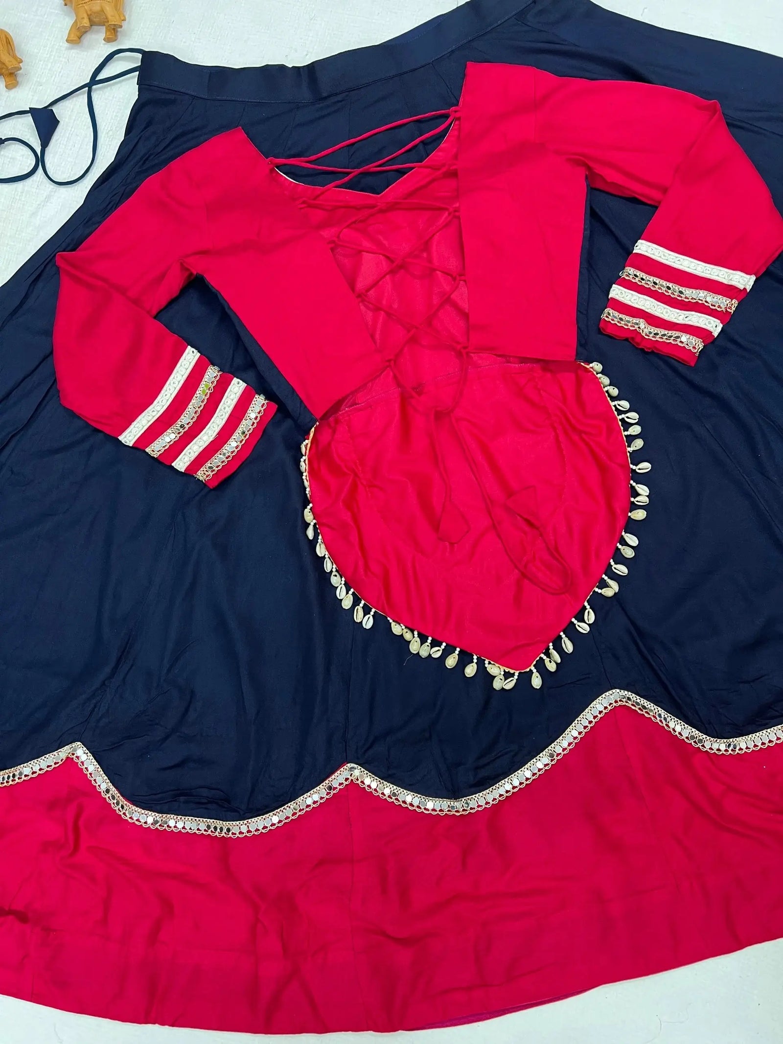 Flat lay showing back of pink lace-up choli and navy lehenga skirt with scalloped pink border