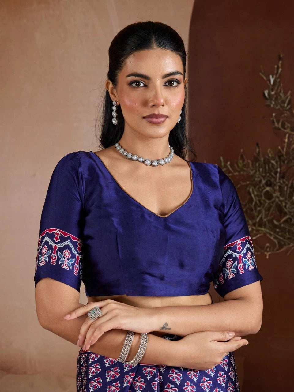 Woman wearing a blue blouse with floral patterns and a matching skirt against a brown background