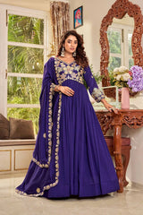 Woman in a purple traditional outfit standing in a decorated room with a mirror and window.