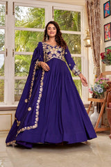 Woman in a purple traditional outfit standing in a room with large windows and decorative elements.