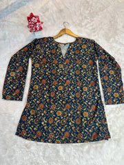 Floral patterned top on a hanger against a textured white background