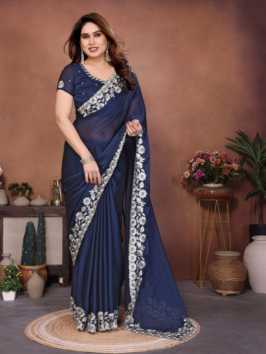 Woman wearing a blue saree with white floral patterns against a brown background