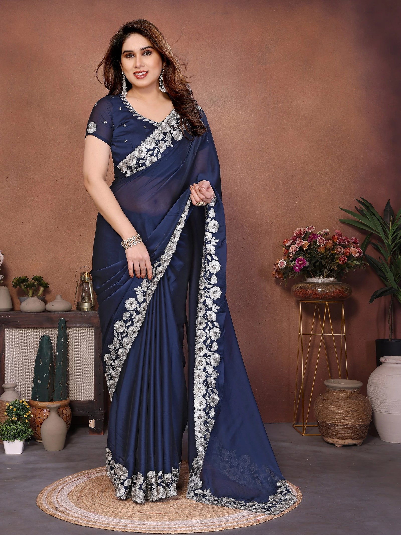 Woman wearing a blue saree with white floral patterns against a brown background