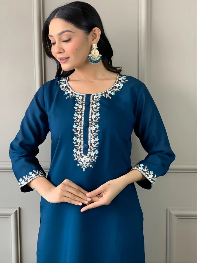 Woman wearing a blue embroidered dress with a neutral background