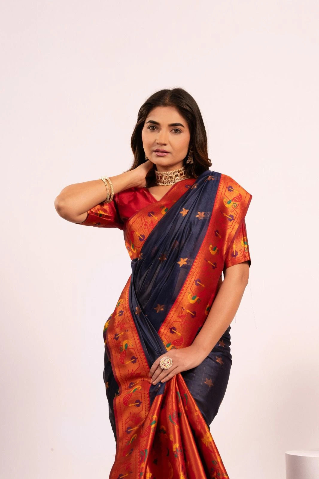Woman wearing a traditional saree with a red and blue pattern on a white background