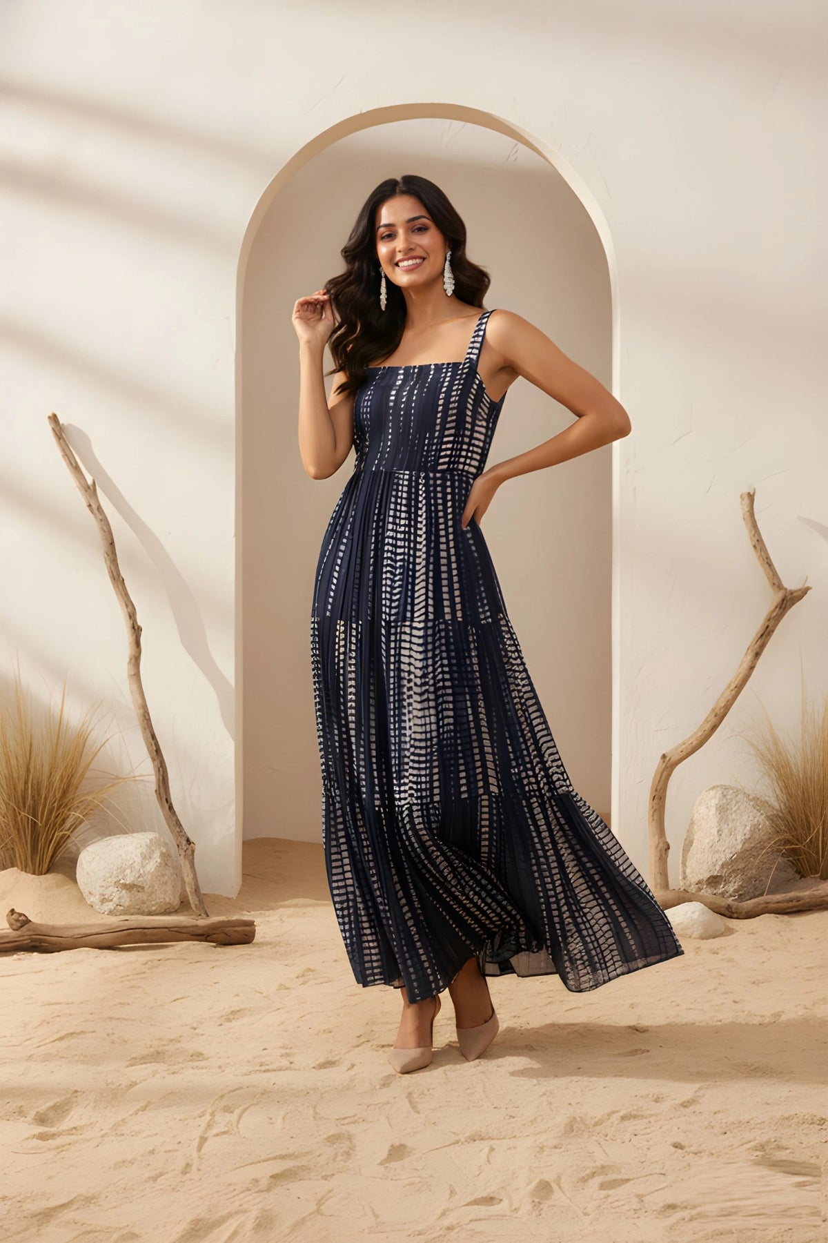 Woman in a blue patterned dress standing in a desert-like setting with archway and rocks.