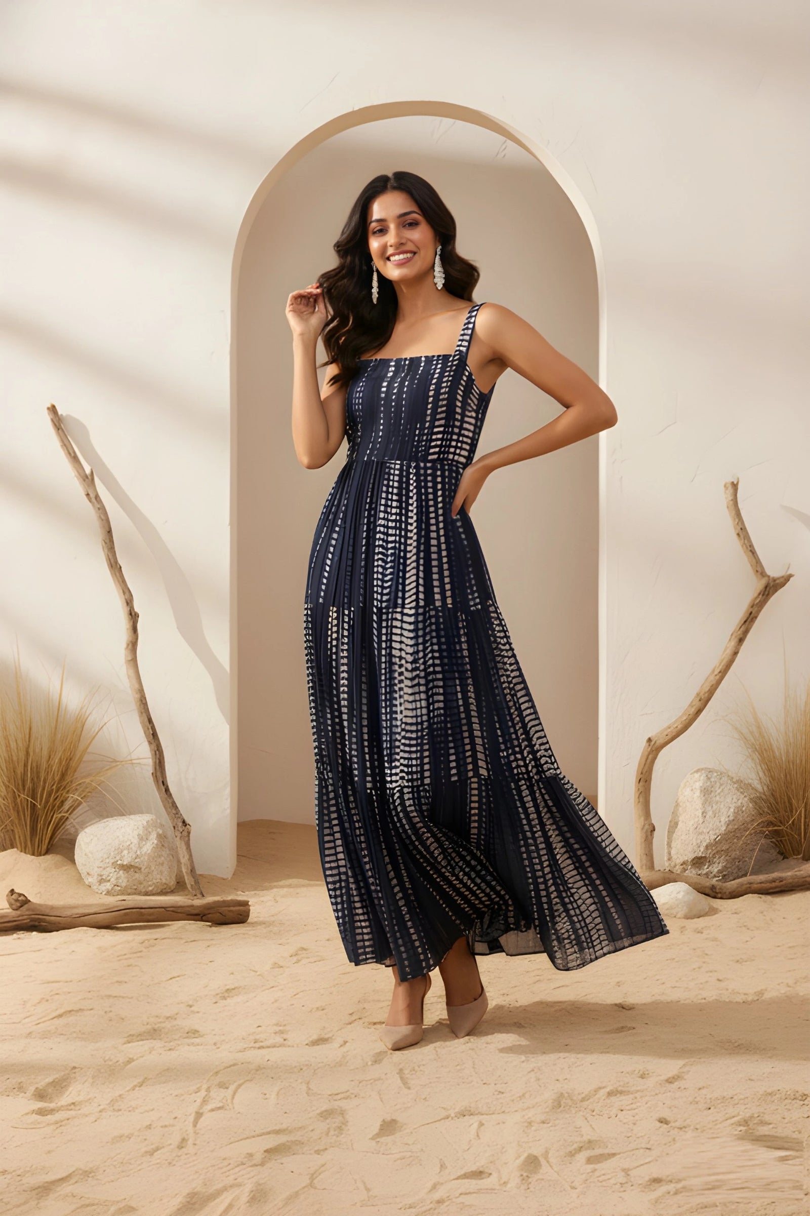 Woman in a blue patterned dress standing in a desert-like setting with archway and rocks.