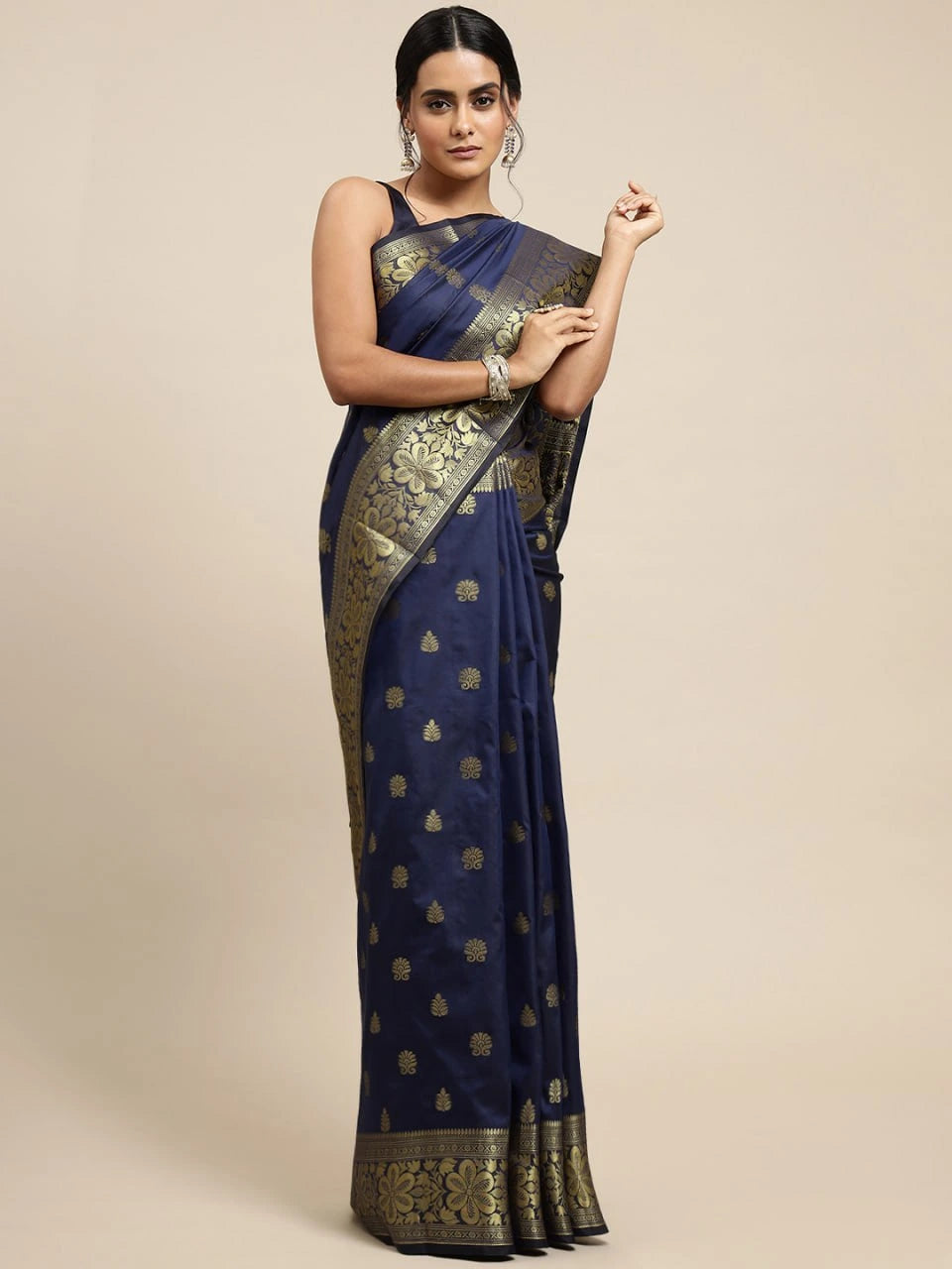 Woman wearing a navy blue saree with gold patterns on a beige background