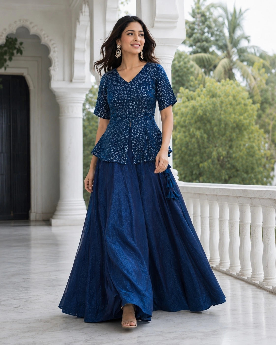 Woman wearing a blue traditional outfit standing on a balcony with greenery in the background