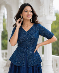 Woman wearing a blue patterned top and skirt outdoors.