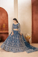 Woman in a blue embroidered traditional outfit standing against a neutral background