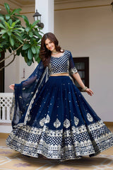 Woman in a traditional navy blue and white embroidered outfit standing indoors.
