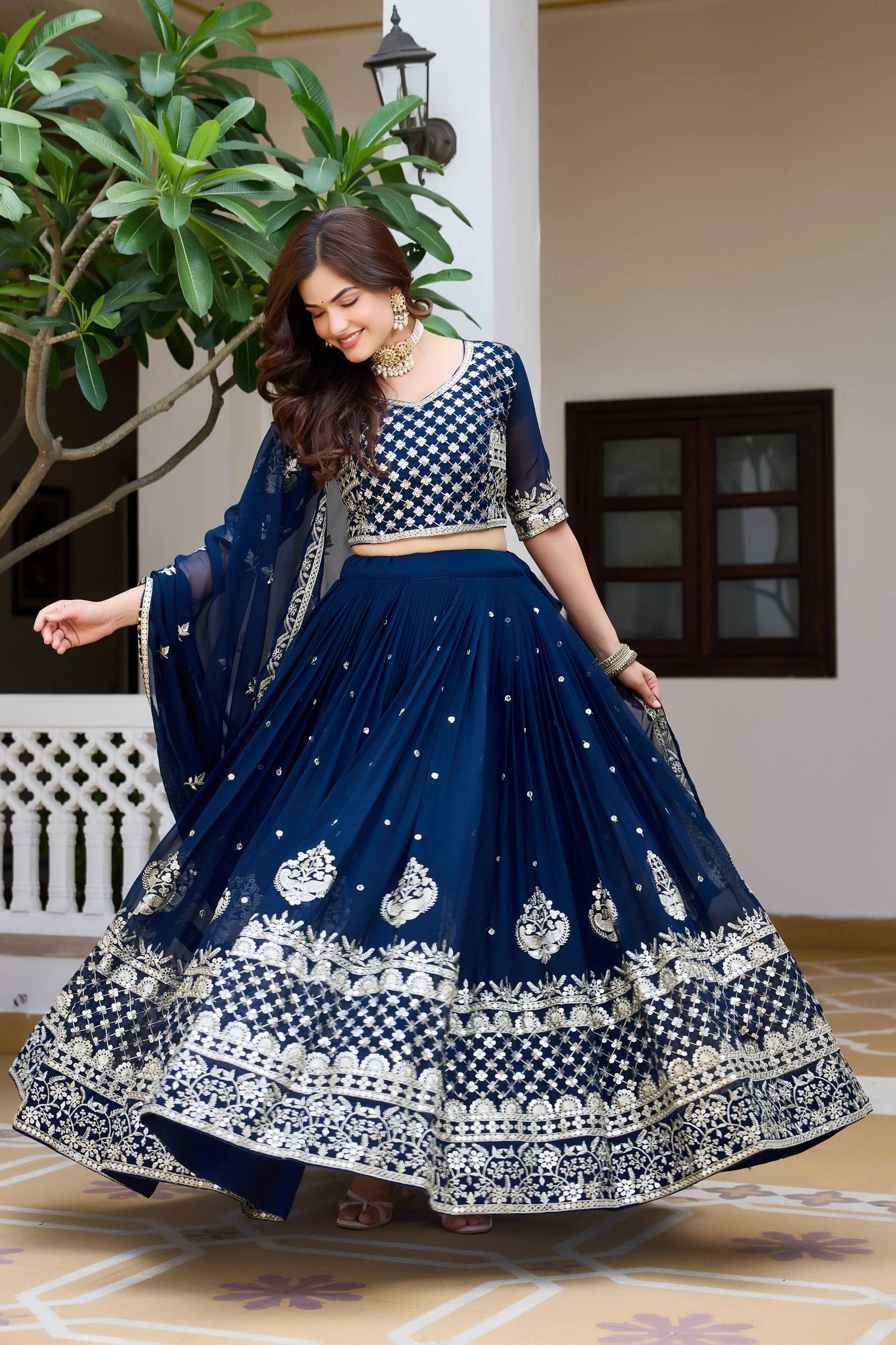 Woman in a traditional blue and white outfit with a patterned background