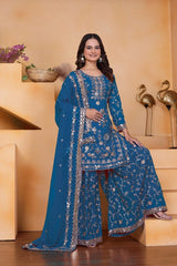 Woman in a blue embroidered traditional outfit standing on steps with a neutral background