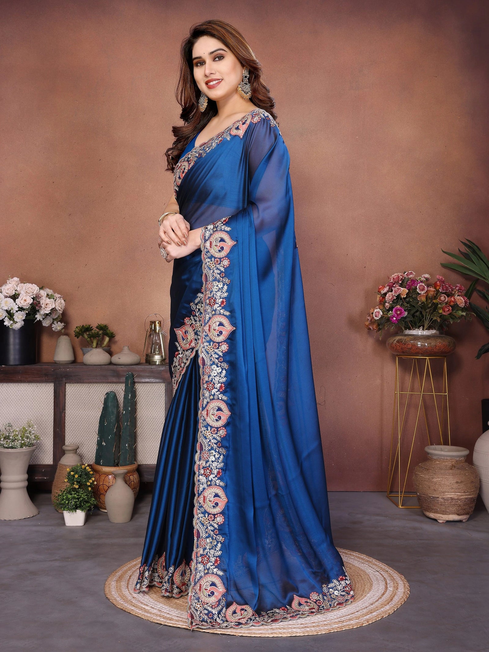 Woman wearing a blue saree with floral patterns in an indoor setting.