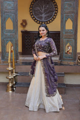 Woman in a traditional outfit standing in a decorated room with ornate wall designs.