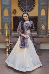 Woman in a traditional outfit with a purple top and white skirt in an ornate setting.