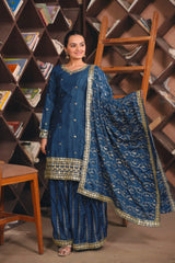 Woman in a blue traditional outfit standing in front of a bookshelf.