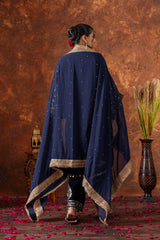 Woman wearing a navy blue embroidered dupatta with gold trim against a brown textured wall.