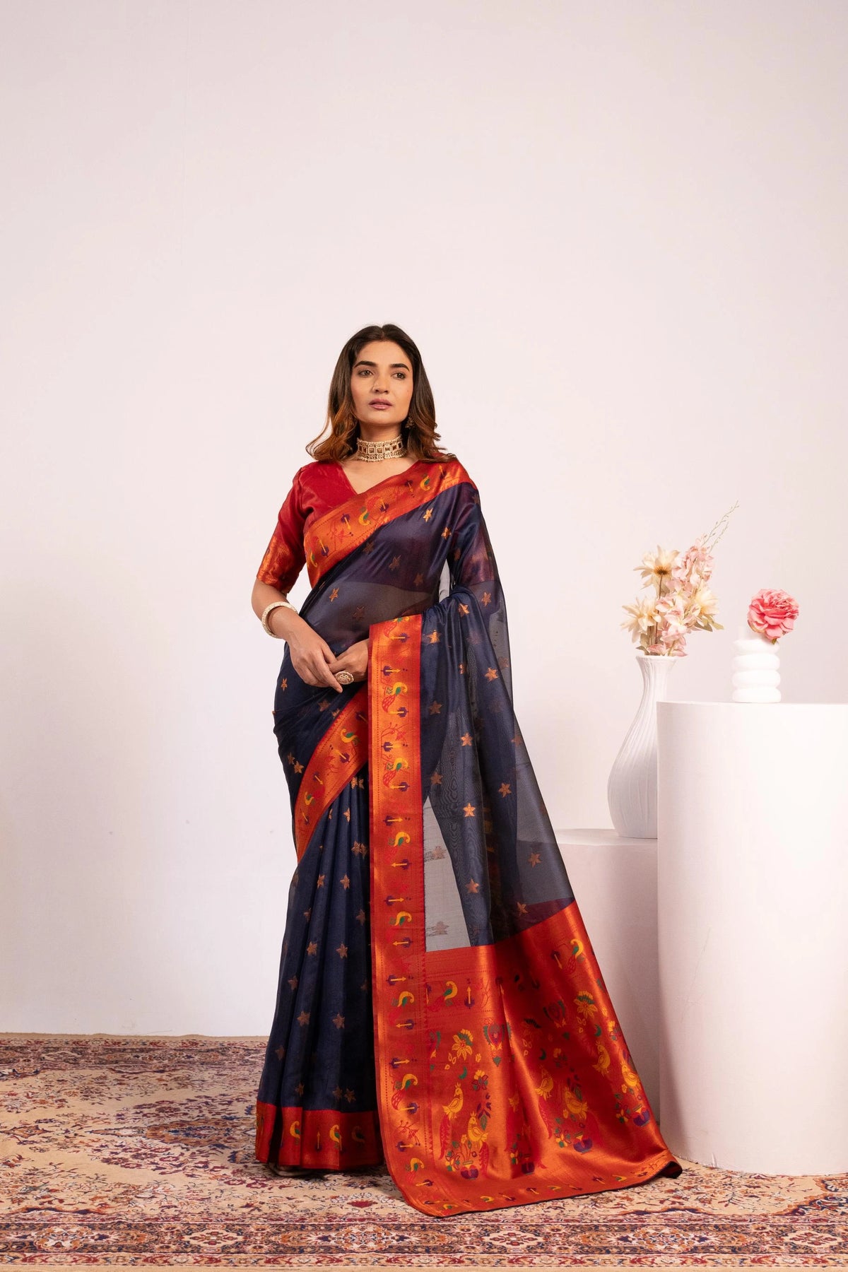 Woman wearing a traditional saree with a red and blue pattern on a white background