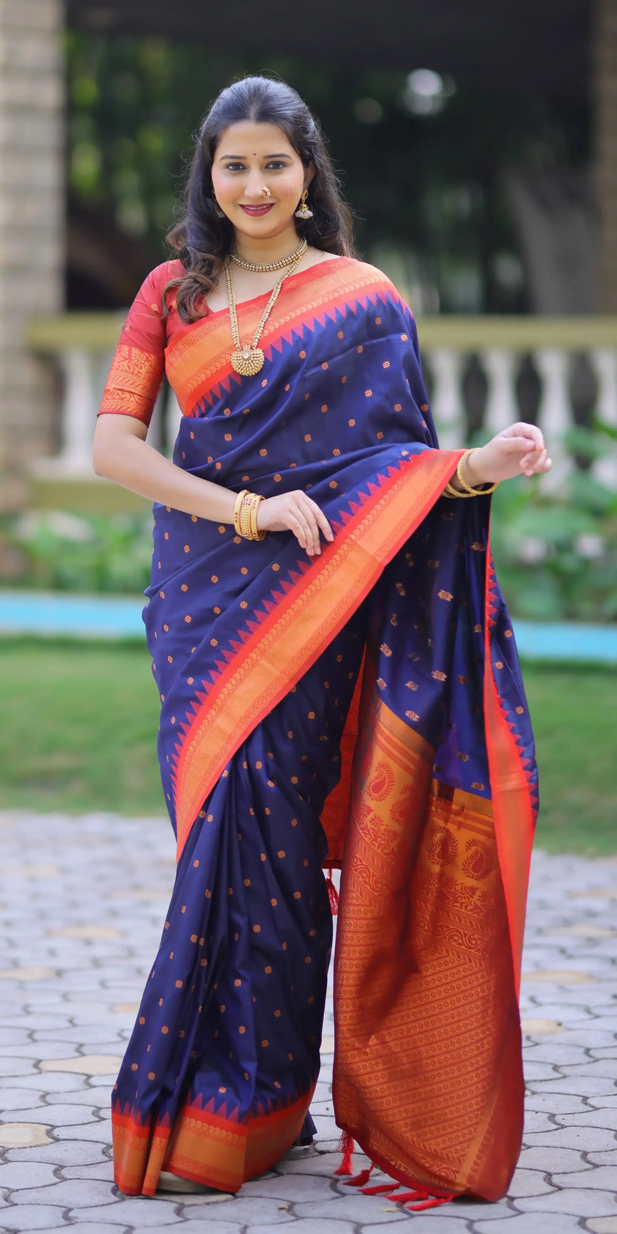 Woman wearing a blue and orange saree with a blurred outdoor background