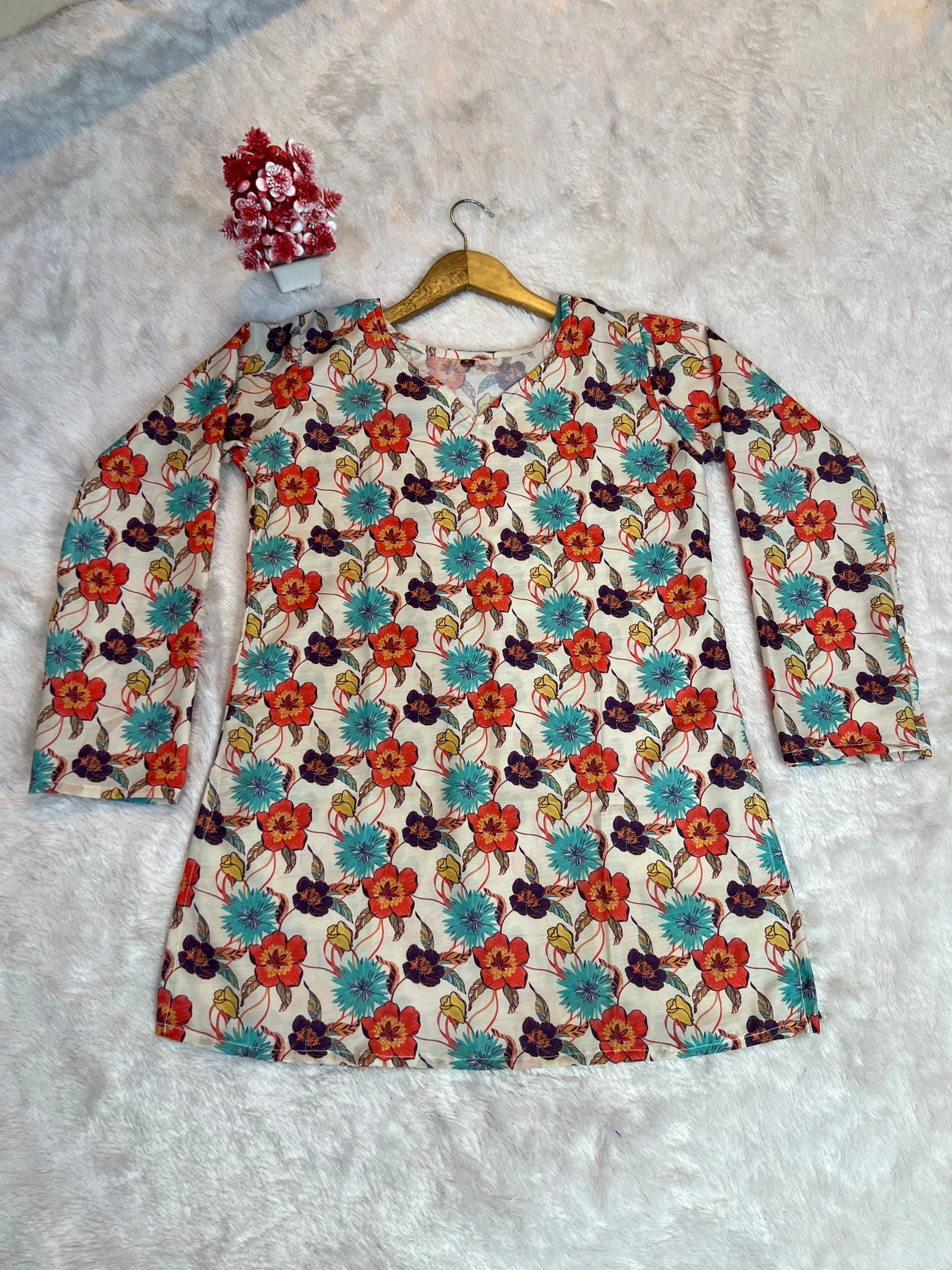 Floral dress with long sleeves on a hanger against a textured gray background