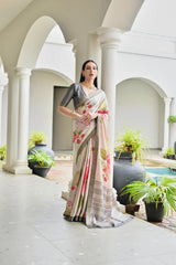 Woman in a saree standing in an elegant outdoor setting with columns and plants.